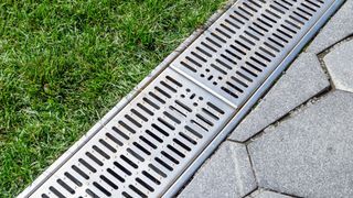 Drainage grill set between a lawn and hardlandscaping