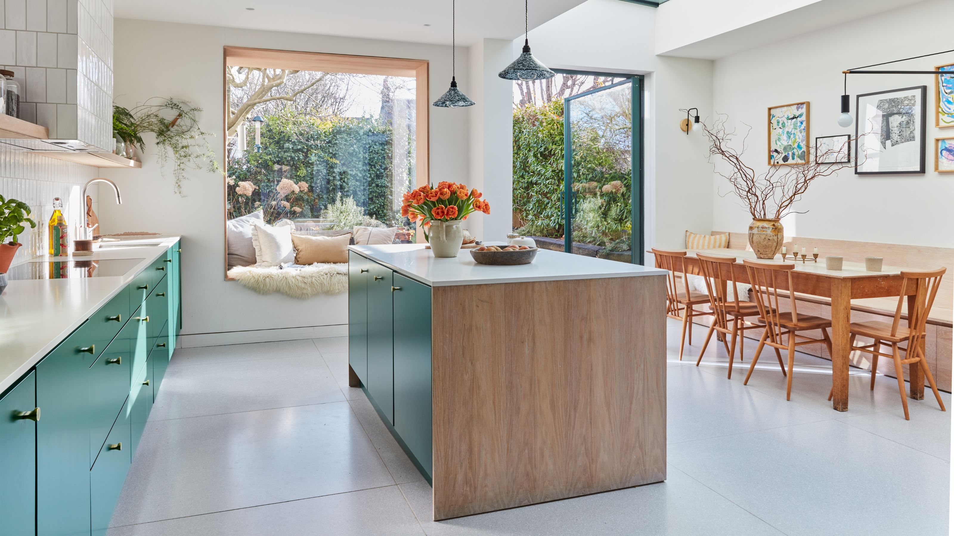 Open plan kitchen diner with blue cabinets and a matching island, and a wooden table and chairs on the right