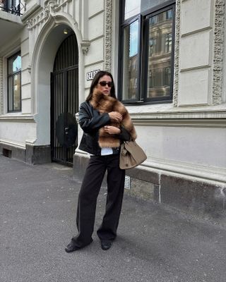 Woman wears Jeanerica wide-leg jeans with a fur scarf and leather jacket.