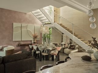 An open plan living area with a large staircase in the background, pink walls, and a marble kitchen island in the foreground