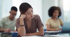 ADHD symptoms: Shot of a sleepy university student in a classroom with her classmates