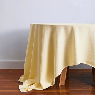 Yellow Bed Threads tablecloth on a dark wood table.