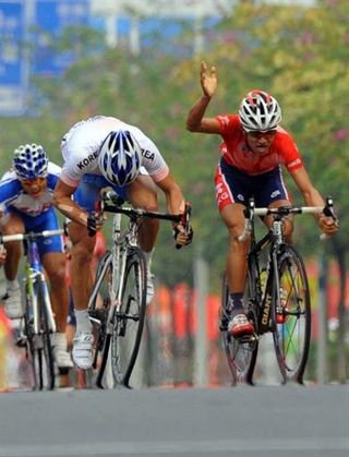 Kam Po Wong (Hong Kong), right, raises his arm in protest over the actions of Park Sung-baek (Korea) in the sprint for the finish line.