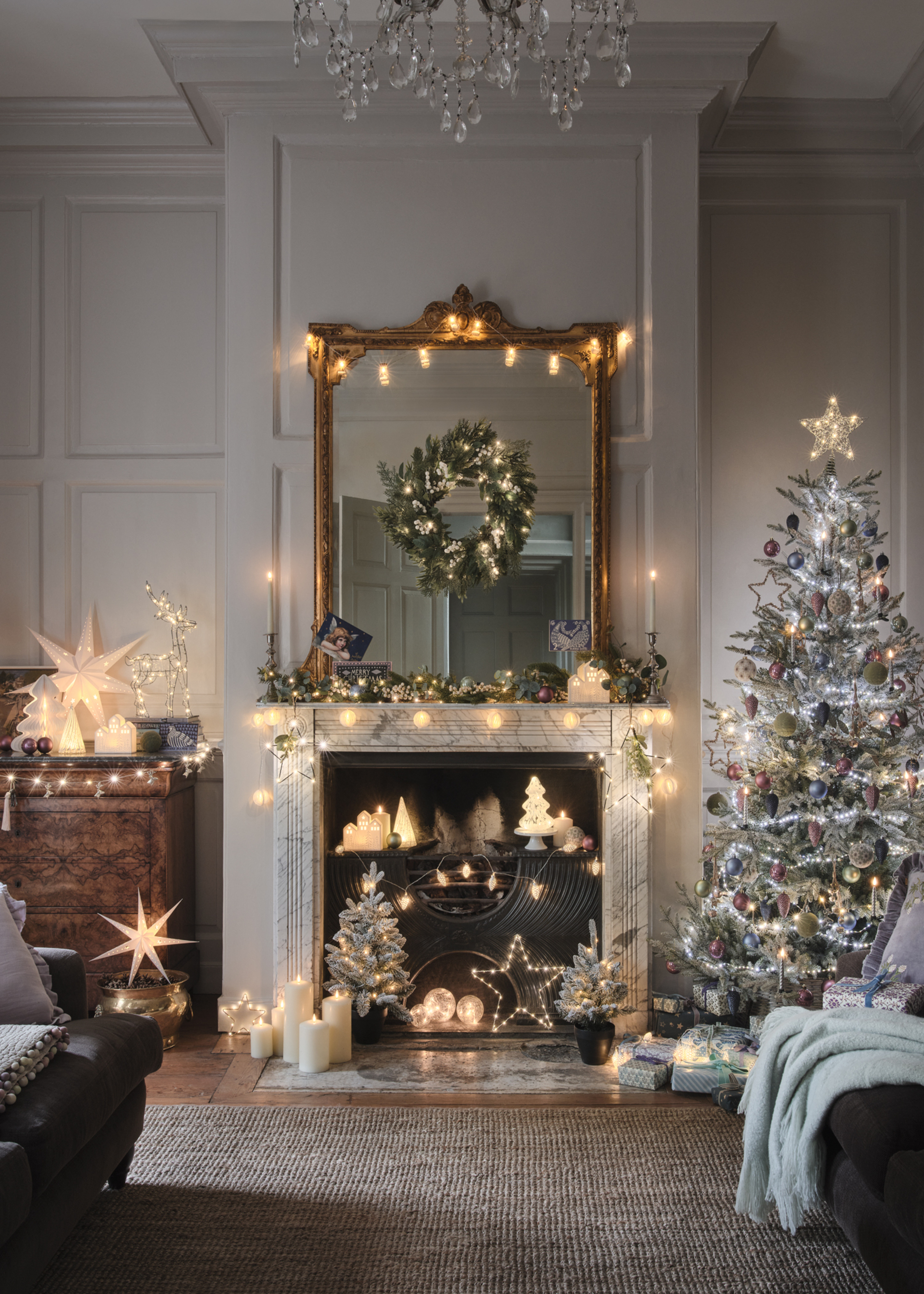 A living room decorated for Christmas with lots of light ornaments in the fireplace and a tree featuring cool white lights