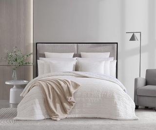 Vera Wang Queen Quilt on a bed against a gray wall.