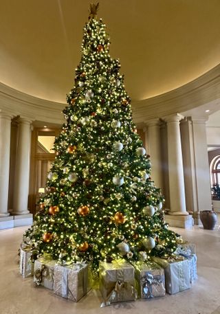 A Christmas tree with white lights and large ornaments surrounded by silver wrapped boxes at The Resort at Pelican Hill in Newport Beach, California