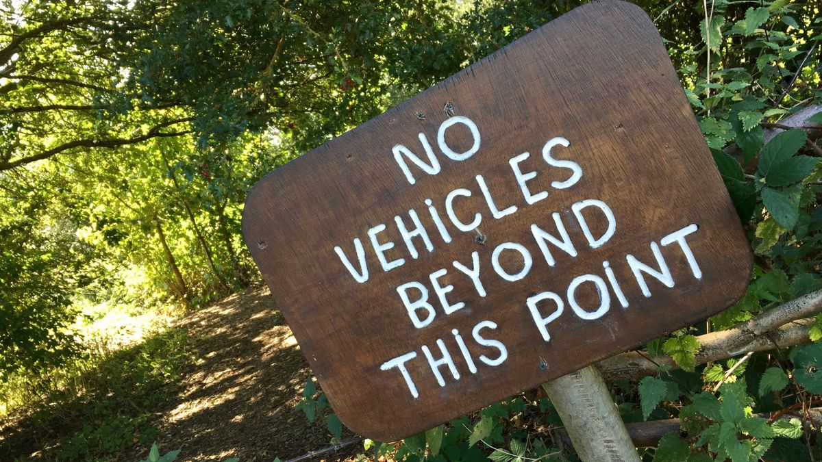 Wooden &#039;no vehicles beyond this point&#039; sign on trail