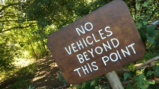 Wooden 'no vehicles beyond this point' sign on trail