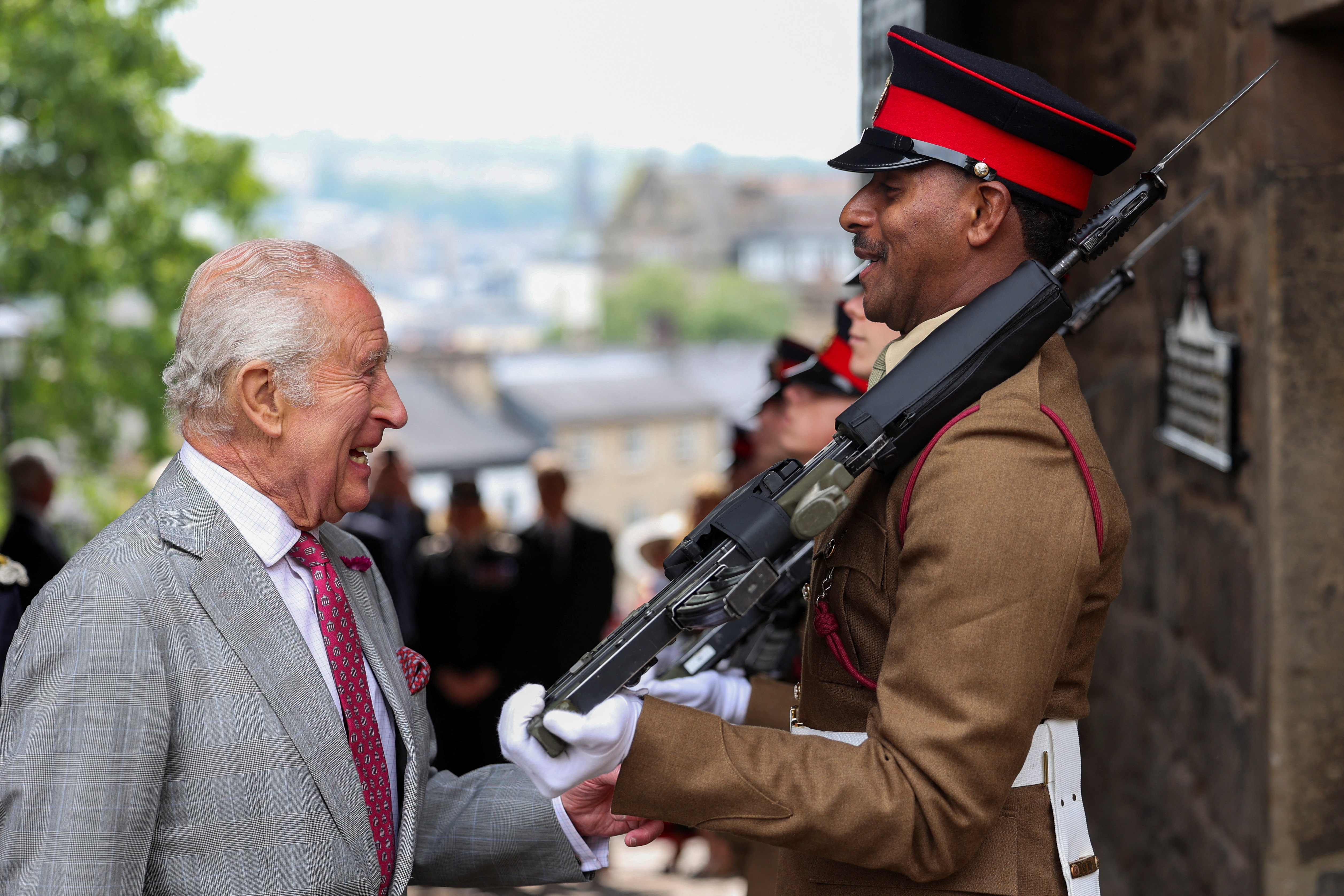 King Charles laughing as he talks to a castle guard in Lancaster