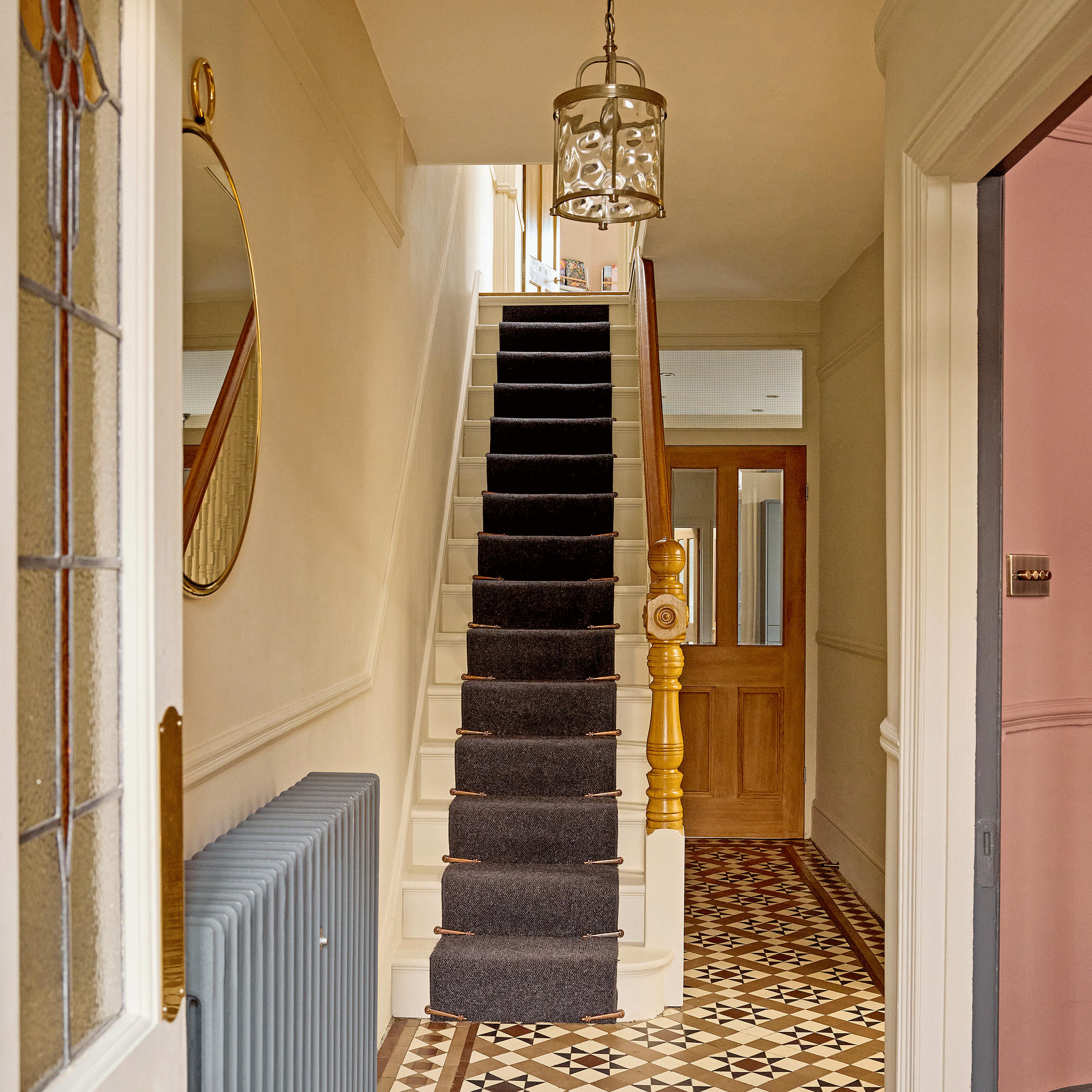 a hallways with traditional Victorian floor tiles a stair runner and pendant light