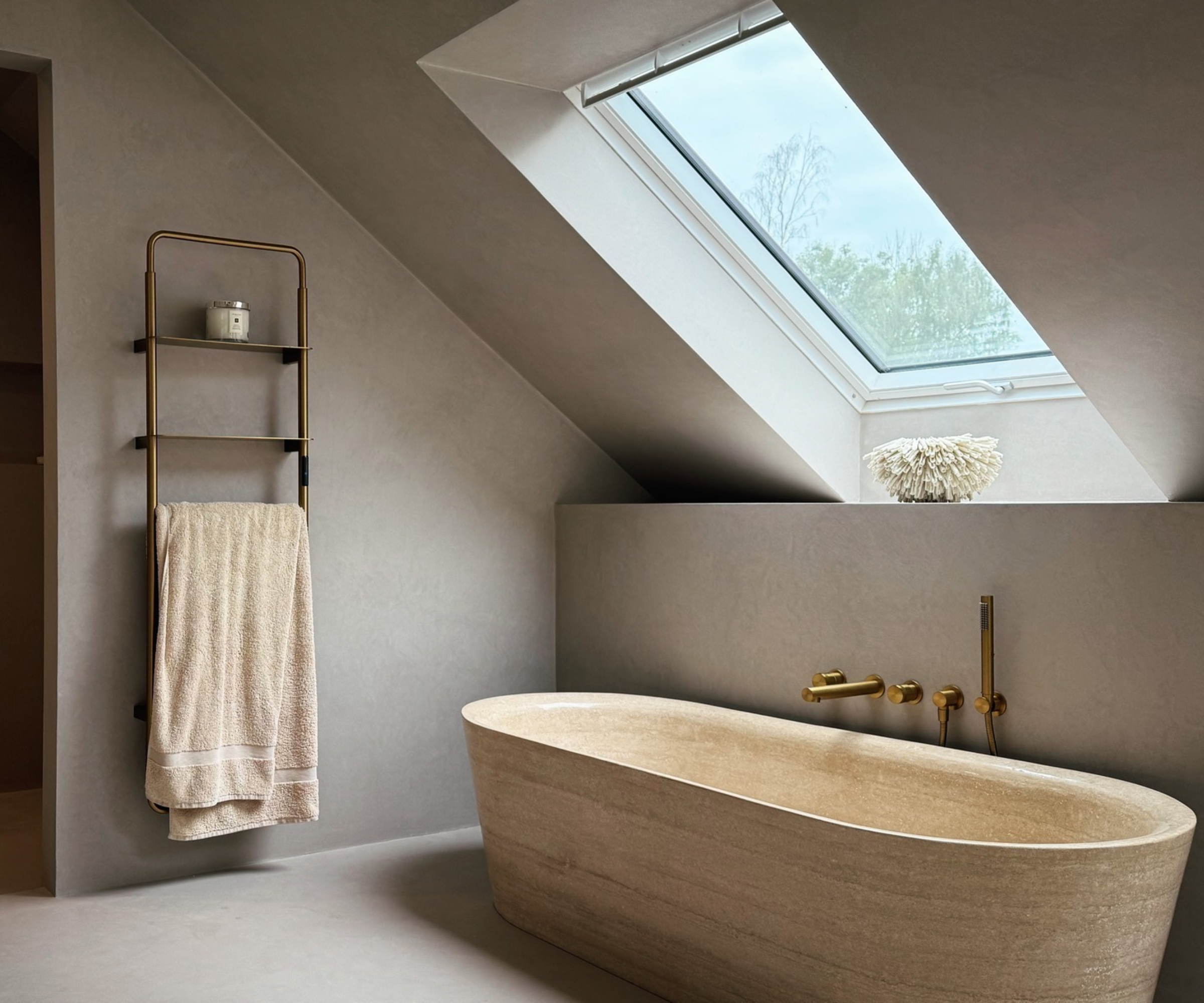 grey bathroom with micro cement walls and cream stone bath