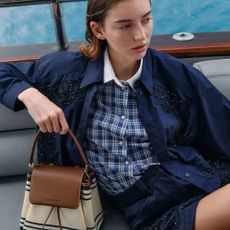 Woman wearing blue outfit on a boat and holding Charles & Keith handbag