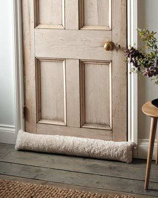 wool draught excluder by wooden door
