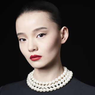 A woman wearing Celine red lipstick and pearls