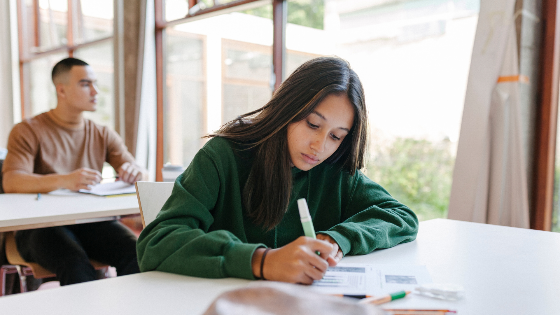 A teenage girl sits at a desk at school studying.