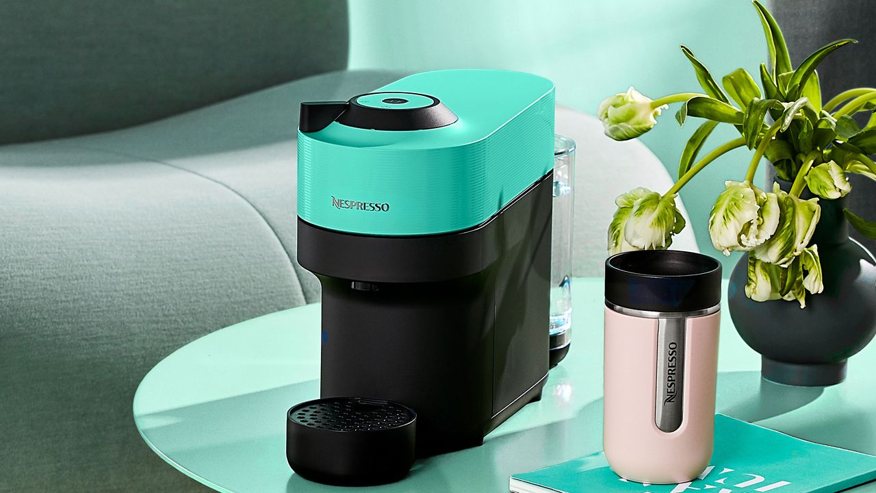 Aqua Nespresso Vertuo Pop machine and pale pink travel mug on aqua coloured coffee table