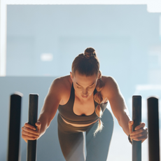 A woman pushing a weighted sled in a gym