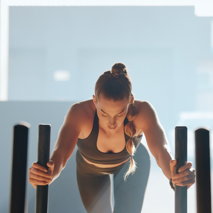 A woman pushing a weighted sled in a gym