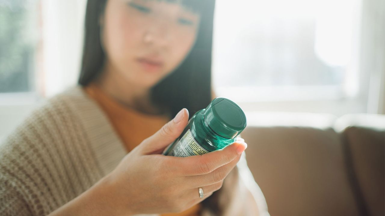 Woman reading supplement packaging 