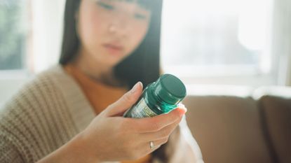 Woman reading supplement packaging 