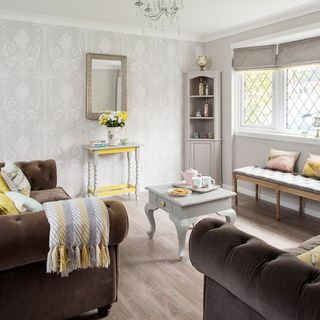 living room with grey designed wall brown sofa and wooden flooring