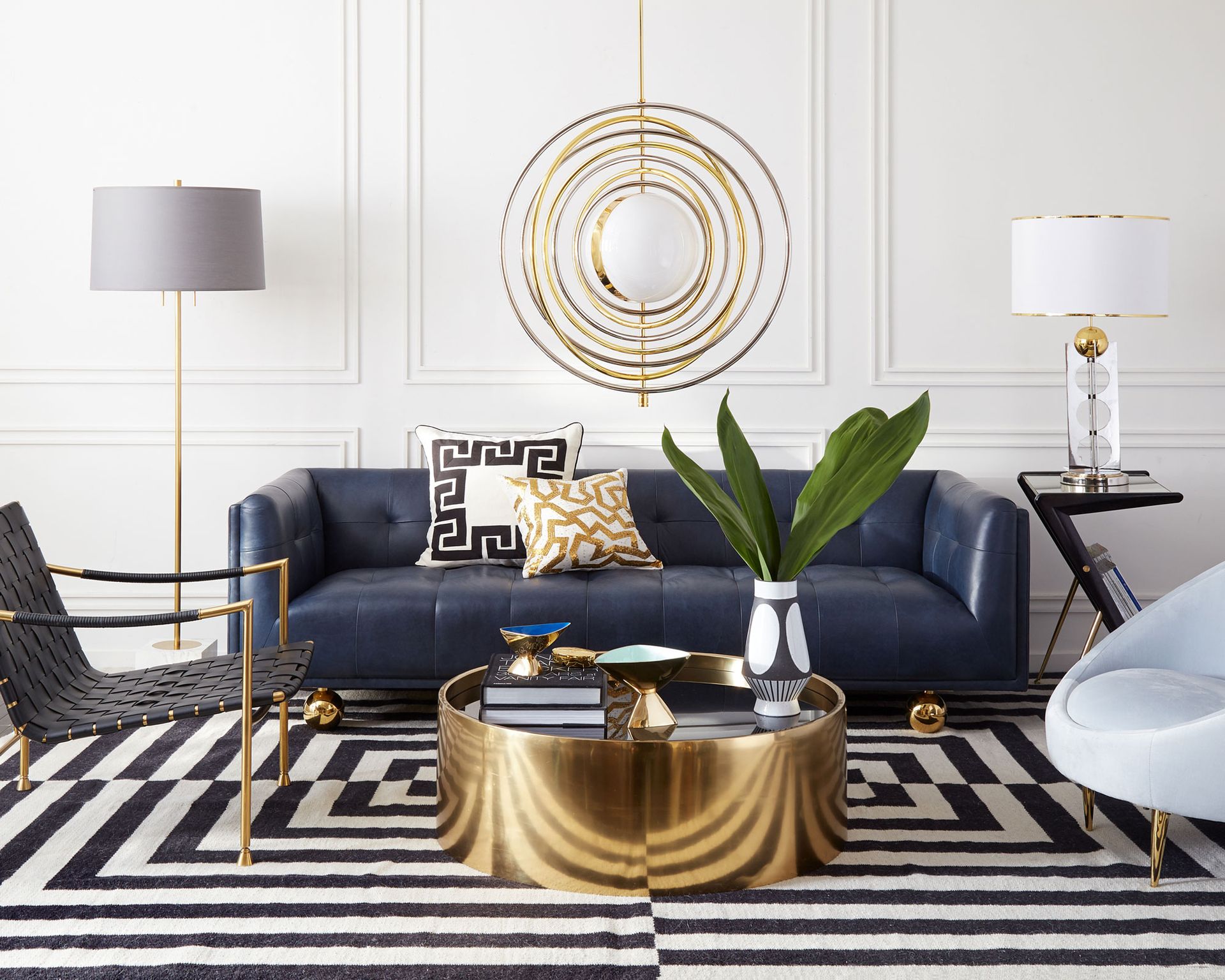 Gold lighting and accents alongside a navy blue Jonathan Adler Claridge sofa illustrating how to plan living room lighting.