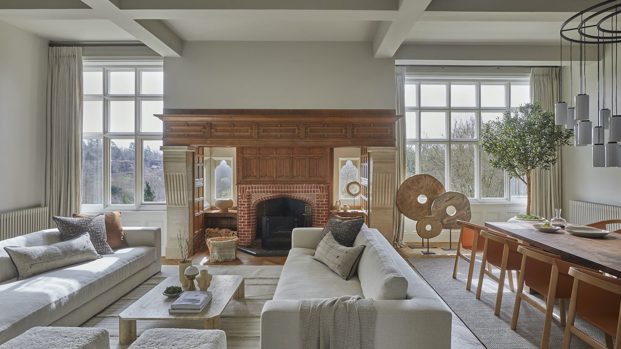 open living room with dining and large fireplace with wooden surround