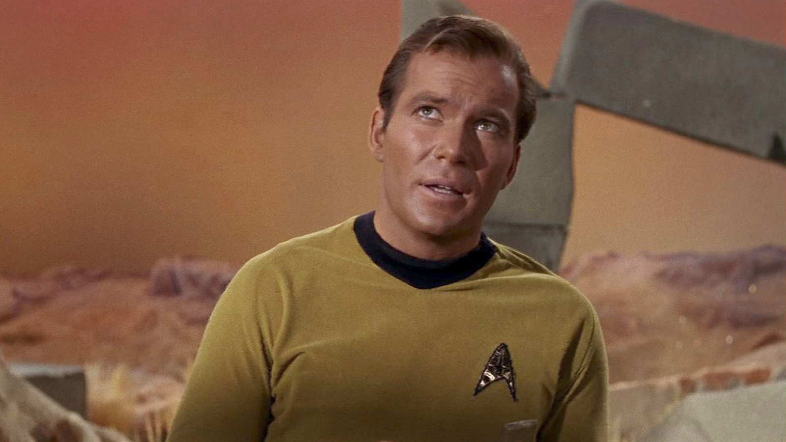 Captura de pantalla de un episodio de Star Trek que muestra a William Shatner como el Capitán James T. Kirk con la icónica insignia de la Flota Estelar.