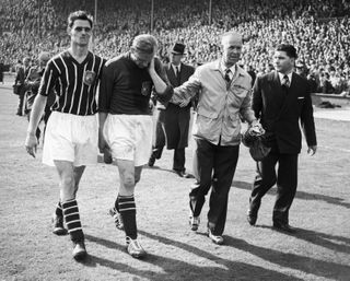 Manchester City goalkeeper Bert Trautmann leaves the pitch at the end of the 1956 FA Cup final, having played the last minutes of the game with a broken neck