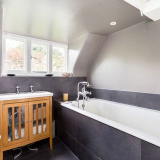bathroom with grey tiled flooring and bathtub