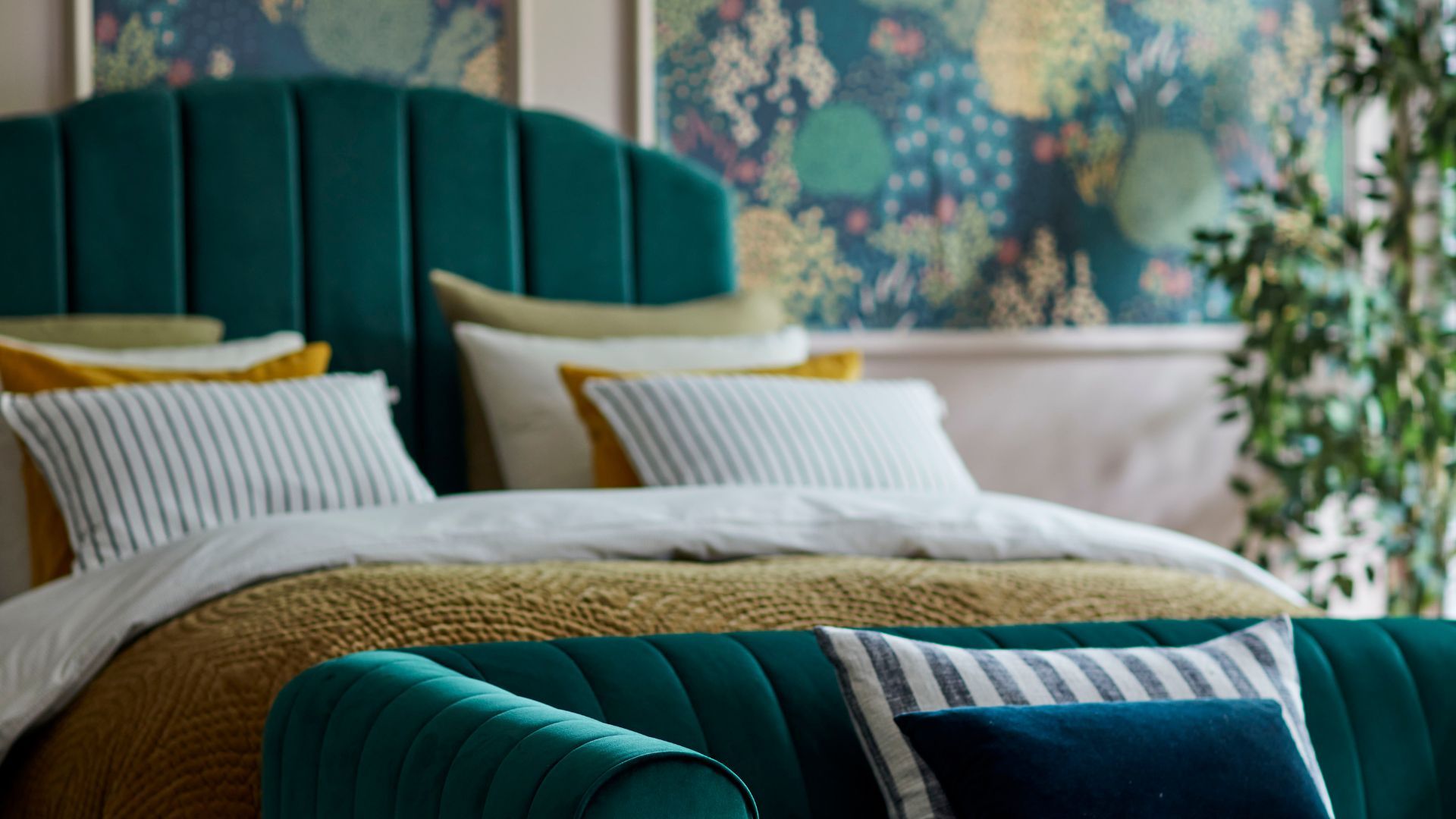 A green velvet bed, dressed with cushions to illustrate how to use the forest green color trend