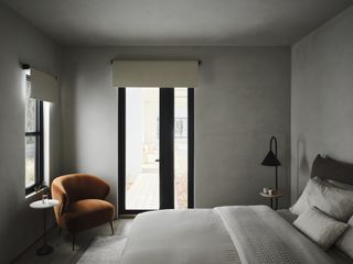 A bedroom fully in gray, with cozy bedding, and an accent chair in the corner in dark orange