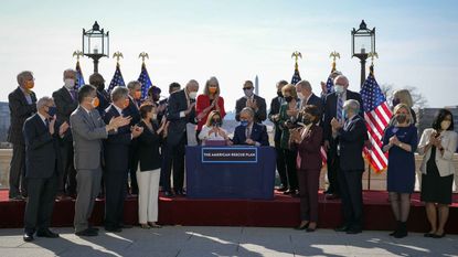 Surrounded by Democratic House and Senate Committee Chairs, Speaker of the House Nancy Pelosi (D-CA) and Senate Majority Leader Chuck Schumer (D-NY) sign the $1.9 trillion COVID-19 relief bill during a bill enrollment ceremony on March 10.