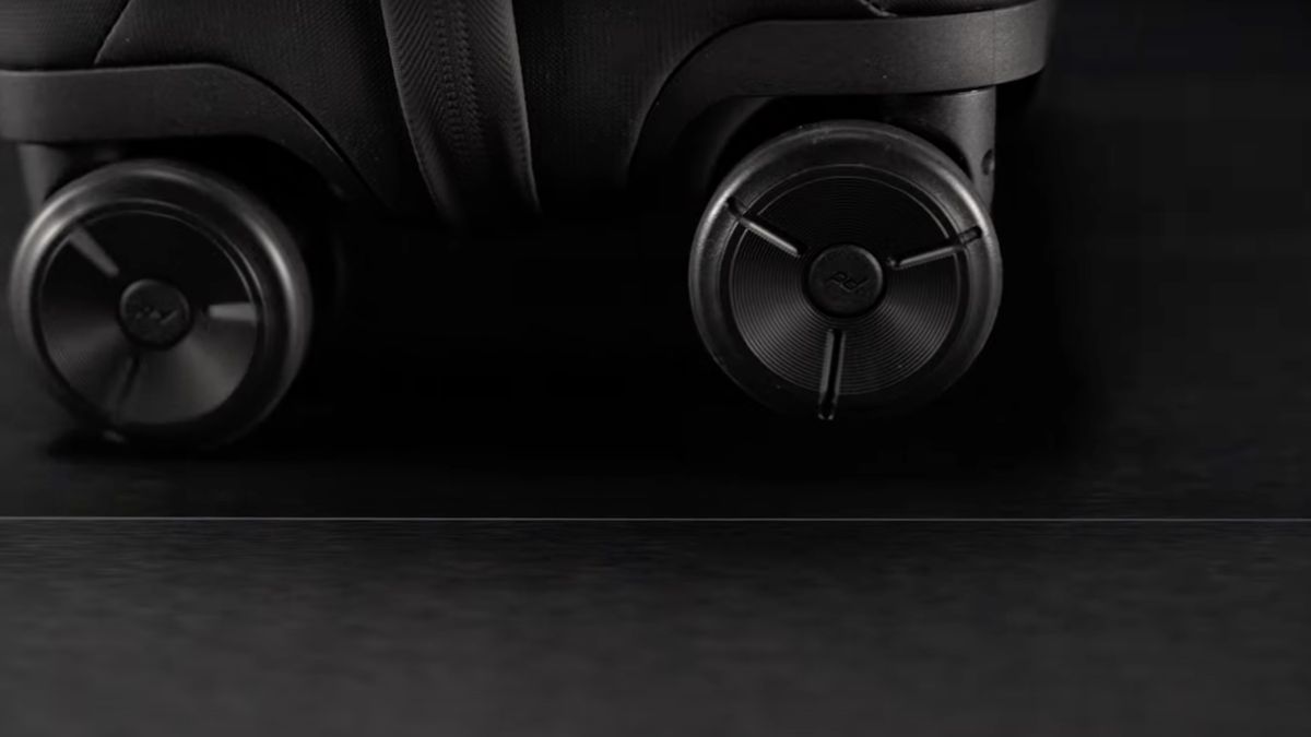 A still capture from the Peak Design video teaser shows black wheels on a black surface