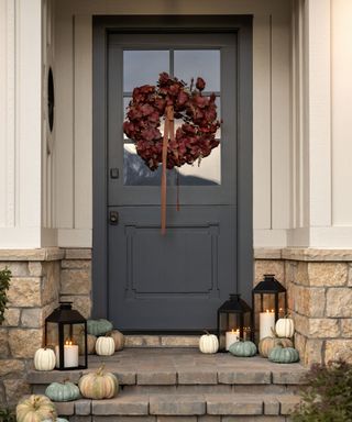 A dark gray front door decorated for fall