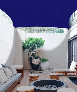 A small decked courtyard patio with a blue deck sail shade