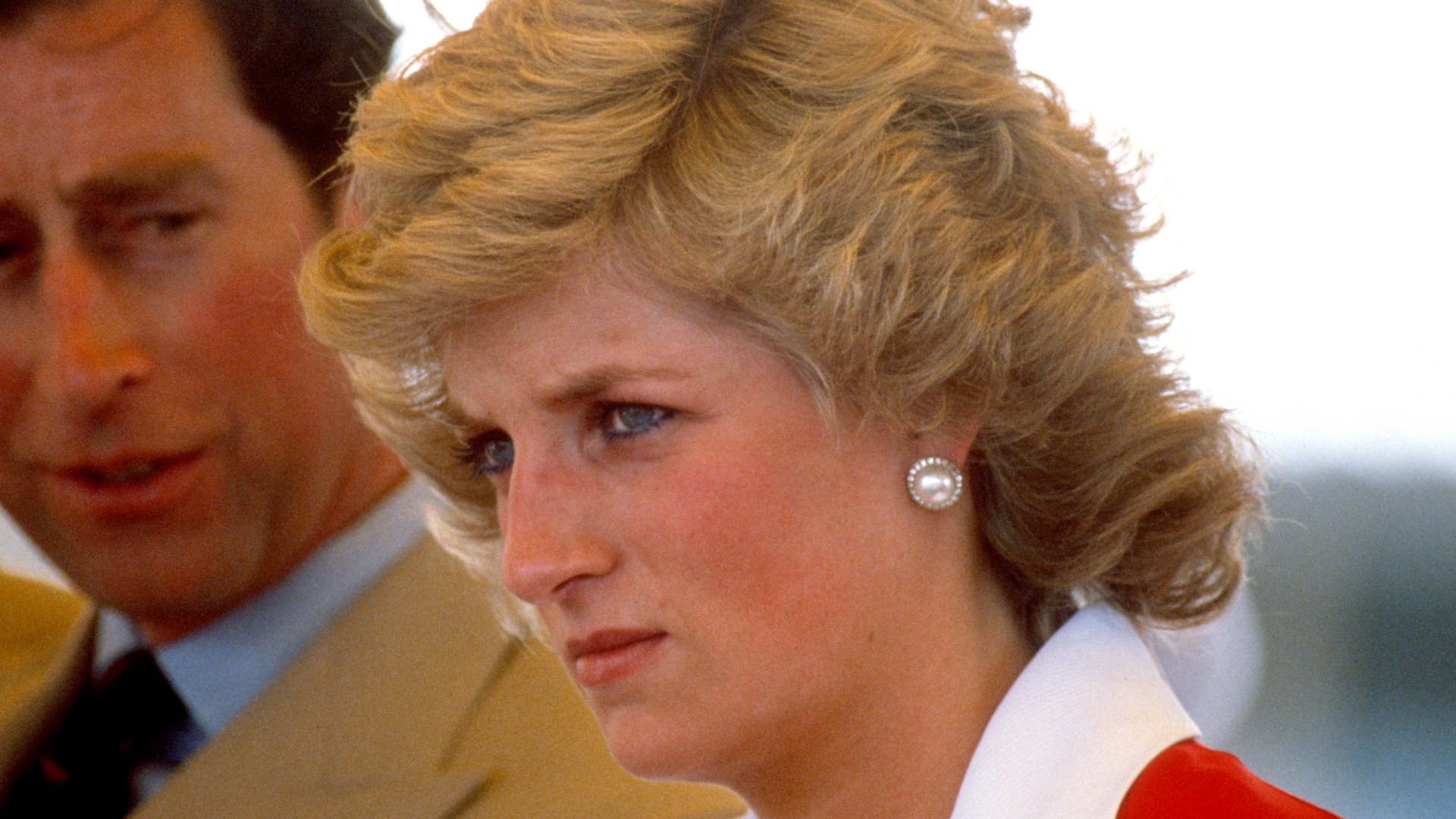 Princess Diana wearing a red and white dress and scowling