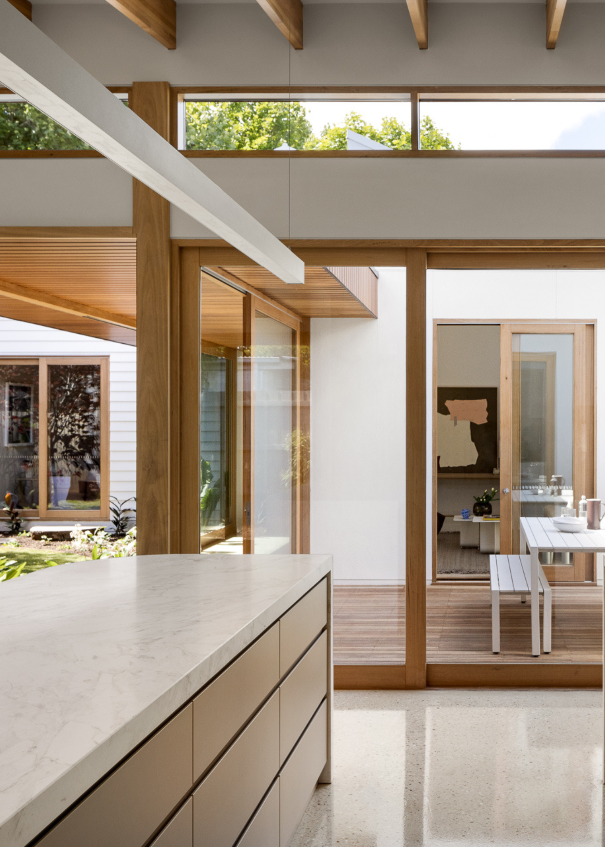 An airy kitchen connected to a deck for outdoor seating and a central garden space