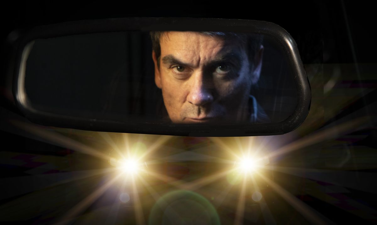 Emmerdale Cain Dingle peering through his car mirror as a pair of headlights beam at him