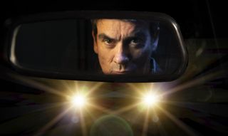 Emmerdale Cain Dingle peering through his car mirror as a pair of headlights beam at him