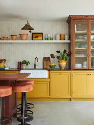 A kitchen with an orange island and yellow cabinets