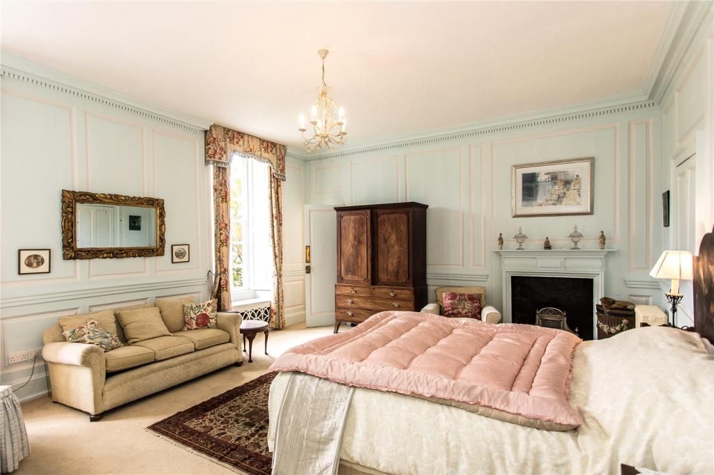 A mint green panelled bedroom with sofa and double bed
