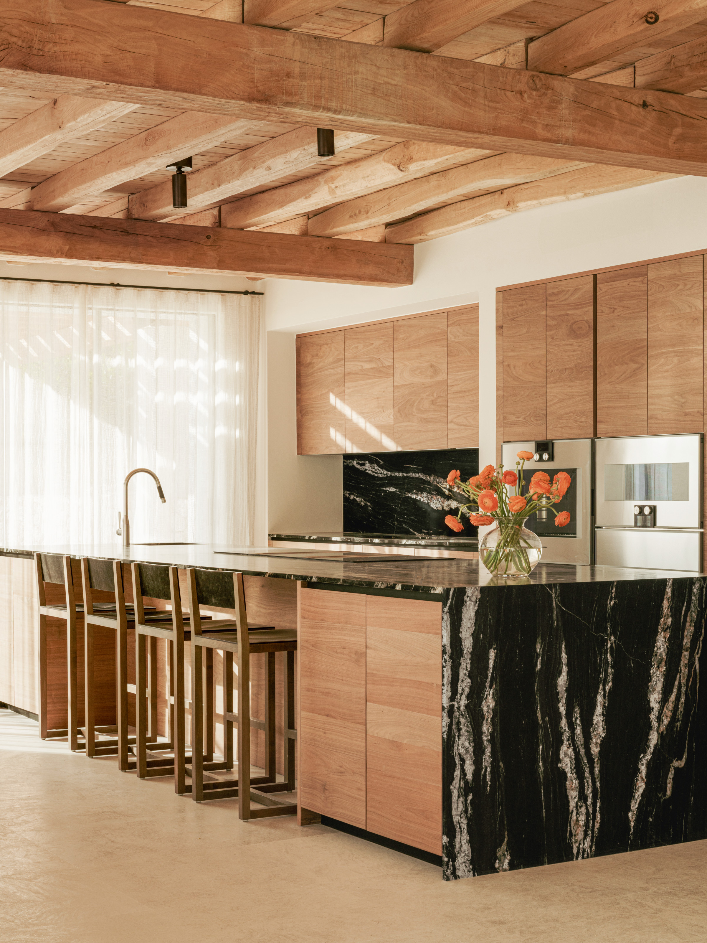 Warm wood kitchen with black marble waterfall island