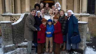 Call the Midwife cast surrounded by snow as they gather on the steps of Nonnatus House for the annual Christmas special clapperboard picture 