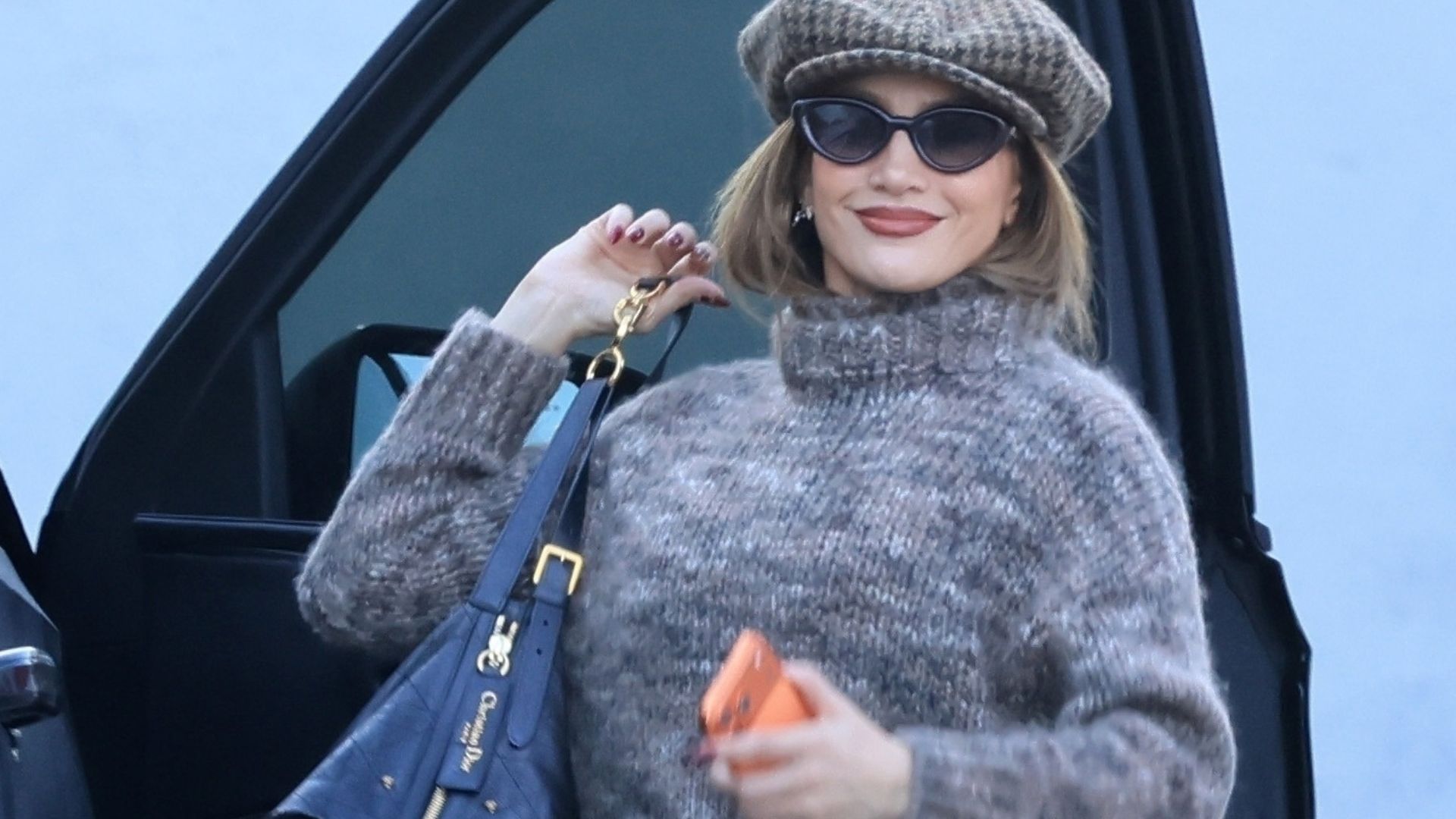 Jennifer Lopez wears a marl knit jumper with brown marl leggings and a knitted baker boy hat.