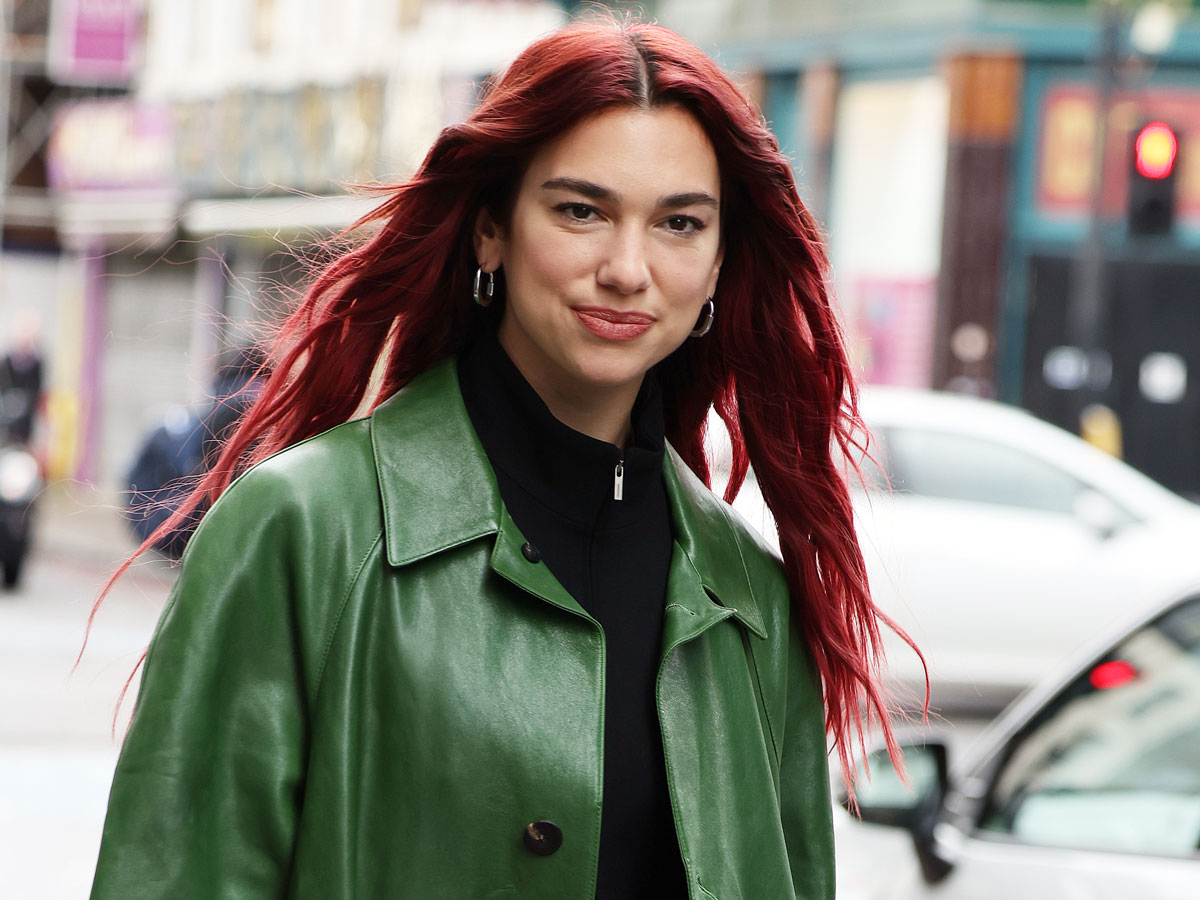 dua lipa, with her hair dyed red, wears a green jacket