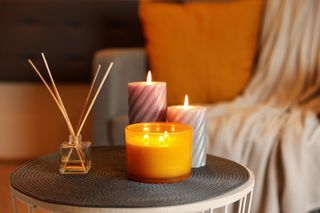 A small side table with three candles and a reed diffuser