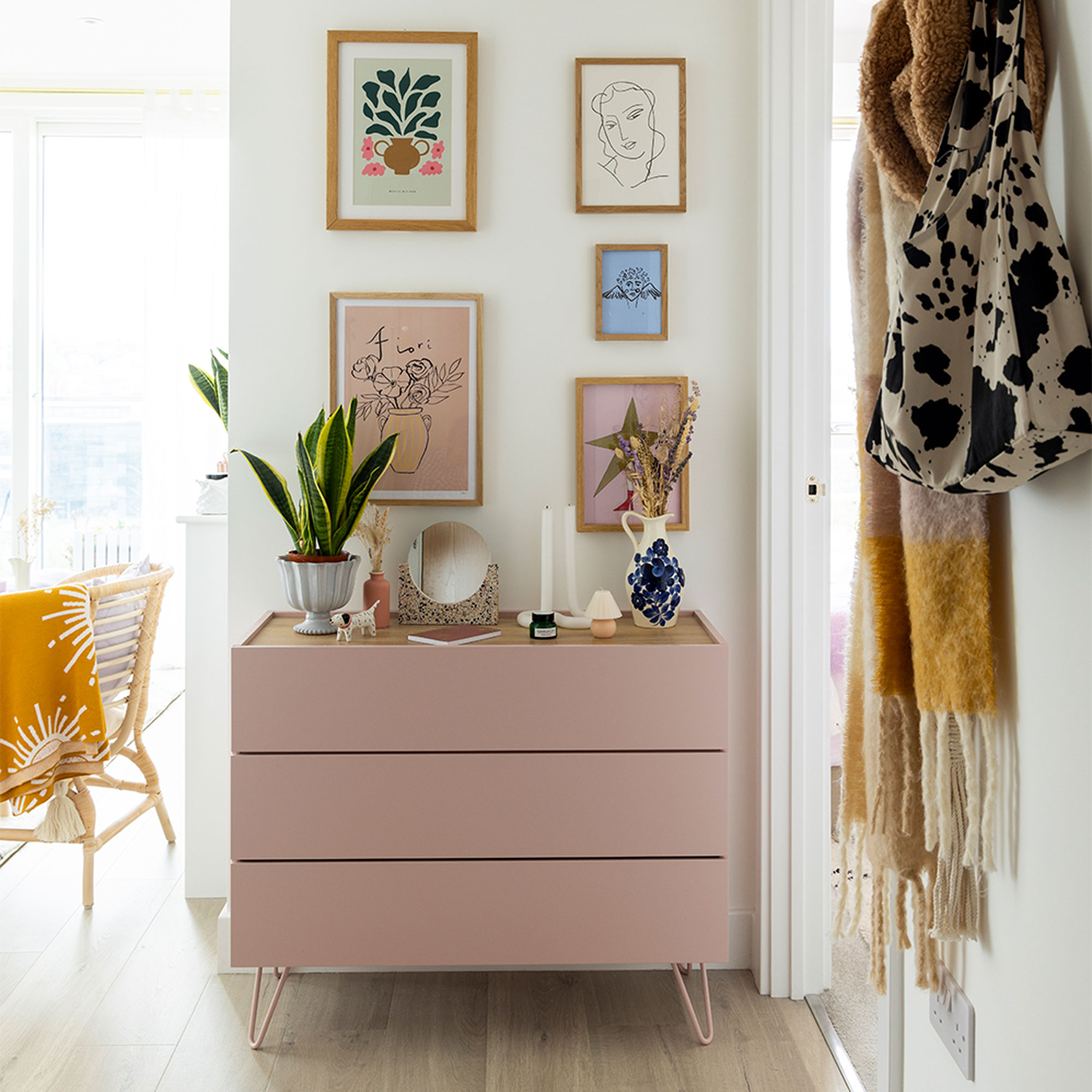 open plan hallway with coat rack and pink chest of drawers