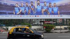Taxi drives past a hoarding of Mumbai Indians cricketers of the Indian Premier League (IPL) cricket tournament