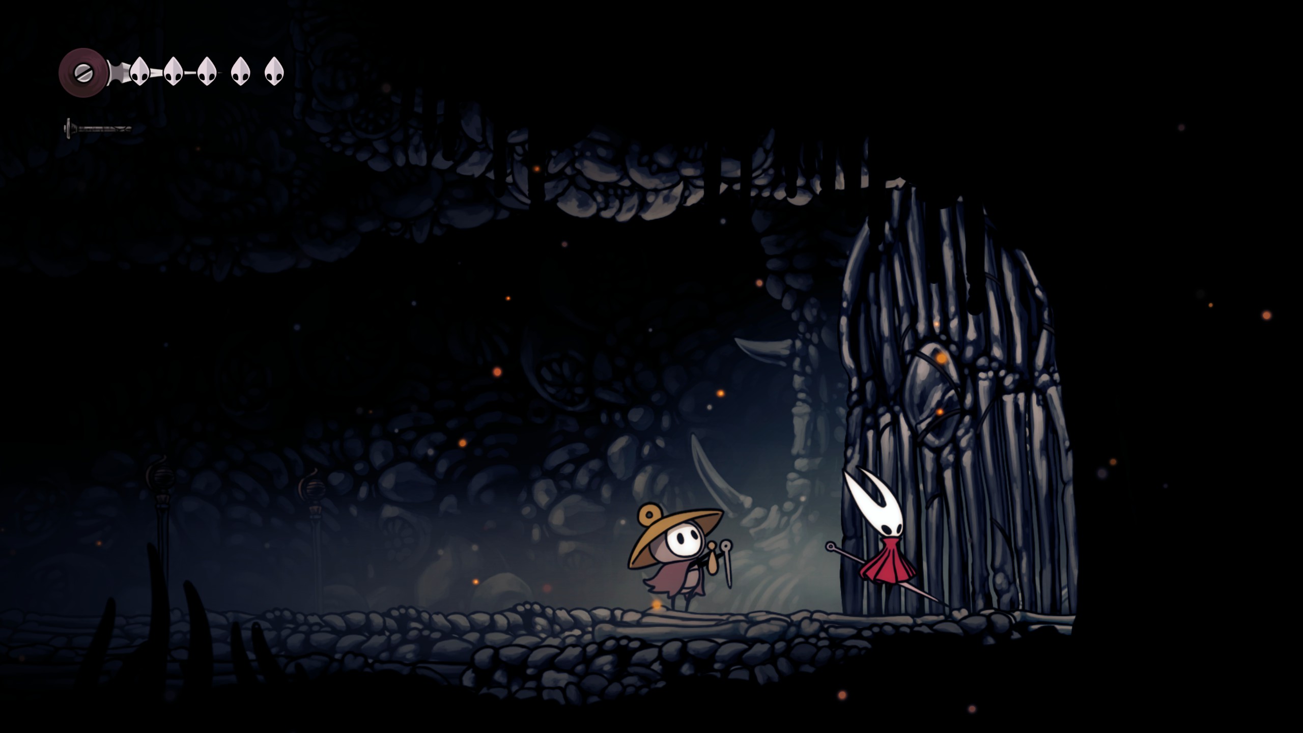A pilgrim standing in front of a bone gate in Hollow Knight Silksong
